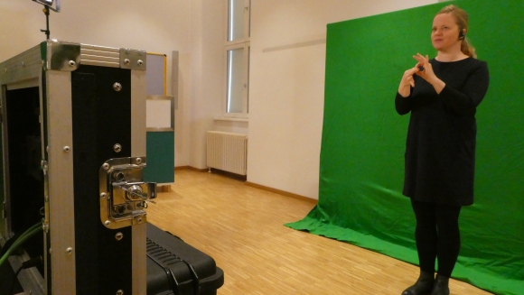 Elke Schaumberger dolmetscht vor dem green screen für die Live-Übertragung