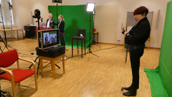 Patricia Brück dolmetscht vor dem green screen für die Live-Übertragung der Fachtage